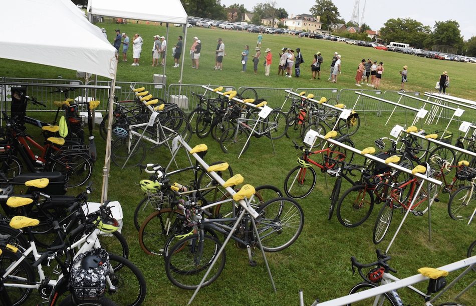 Bicycle Valet Service: Rows of bicycles parked neatly in a valet service area at an outdoor event, with people milling about in the background.