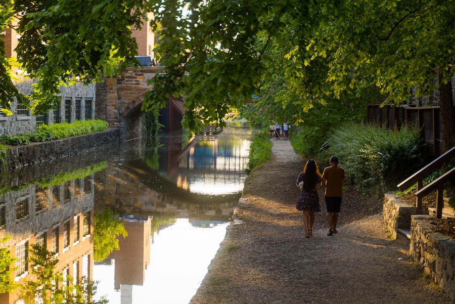 Couple walking along the shaded path beside the Georgetown Canal.