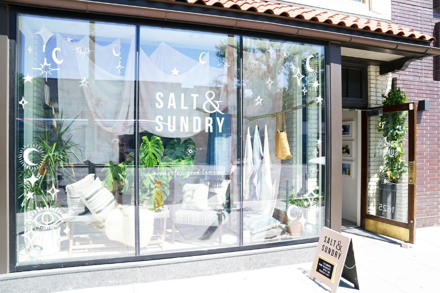 Exterior view of Salt & Sundry Logan Circle storefront with large windows displaying decorative items and plants.