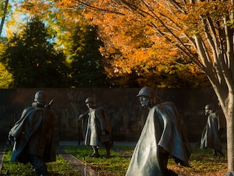 Several figures from the Korean War Veterans Memorial with autumn trees.