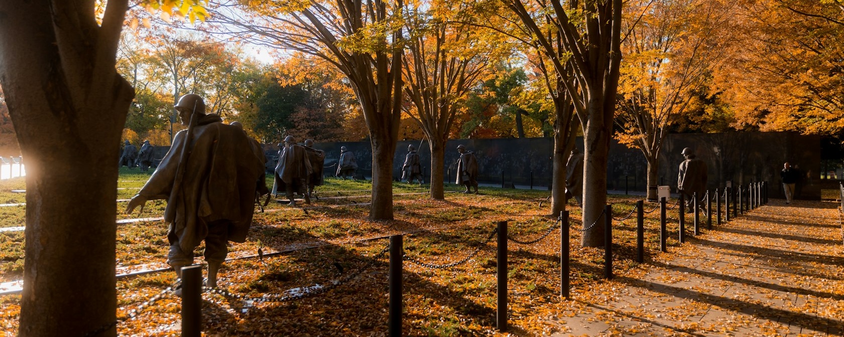 The Korean War Veterans Memorial in evening light with autumn trees and leaves on the ground. 