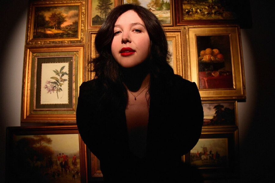 Picture of Lucy Dacus with paintings on wall 