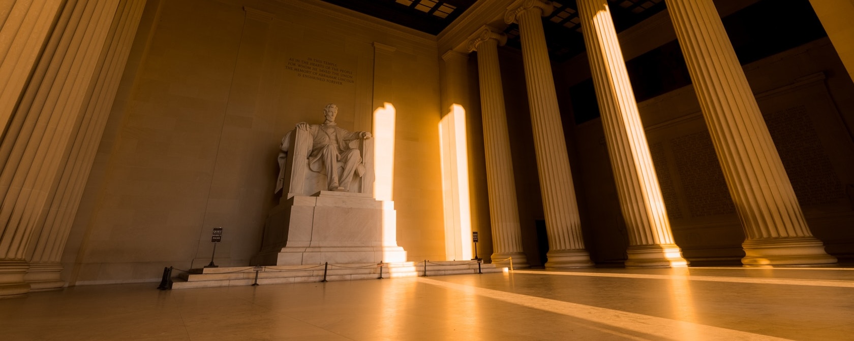 The statue of Abraham Lincoln bathed in golden light inside the Lincoln Memorial.