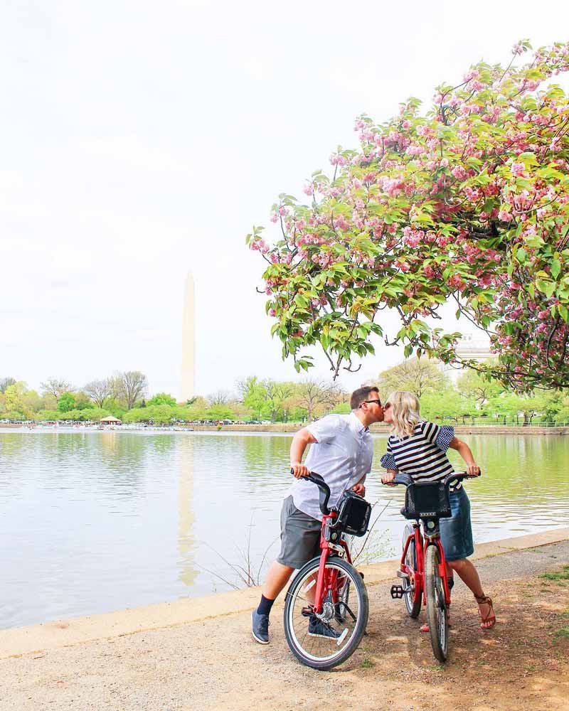 @the.snyder.spot - Husband and wife kissing on bikes in front of the Tidal Basin - Romantic places to visit in Washington, DC