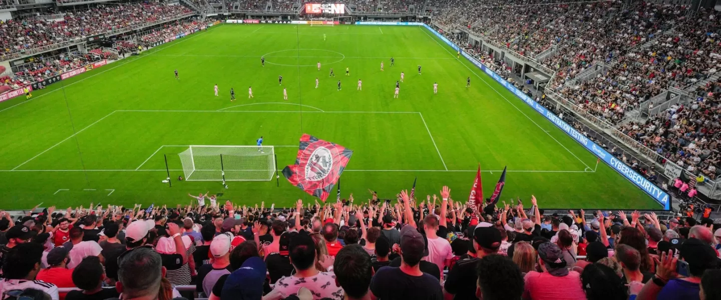 A soccer stadium is packed with fans in red and black at a night game. 
