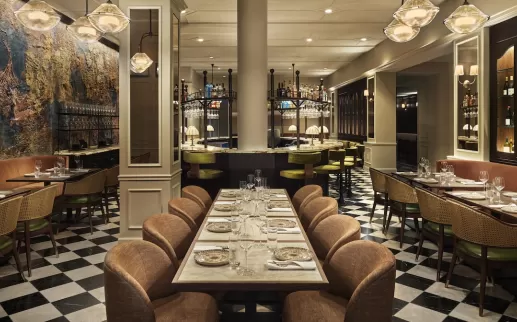 Elegant restaurant interior at Sixty DC featuring warm lighting, modern decor and a central bar with high stools.
