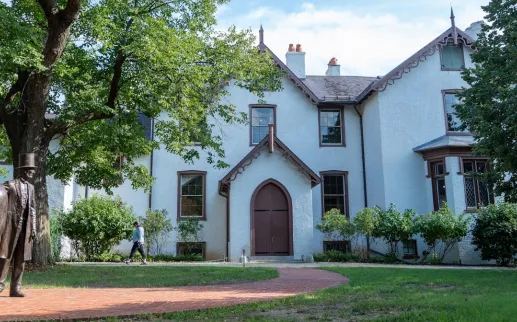 A statue of Abraham Lincoln with his horse stands before the historic Lincoln’s Cottage, surrounded by trees and greenery.