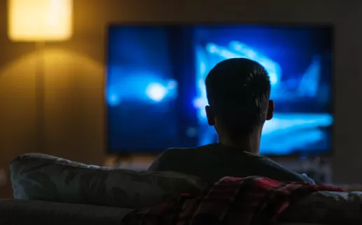 boy facing the television watching it in the dark
