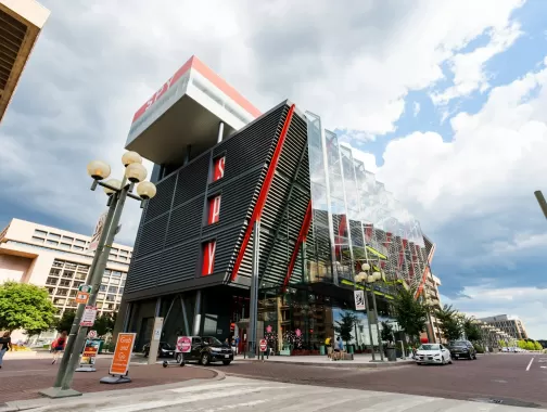 The modern exterior of the International Spy Museum in Washington, DC, featuring a striking design with red accents and glass panels under a cloudy sky.