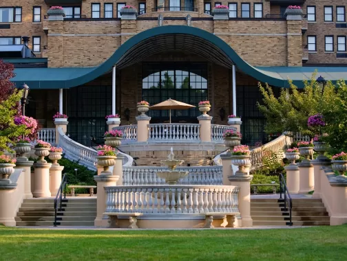 A grand staircase and terrace adorned with flower-filled planters lead to the elegant entrance of the historic Omni Shoreham Hotel in Washington, DC