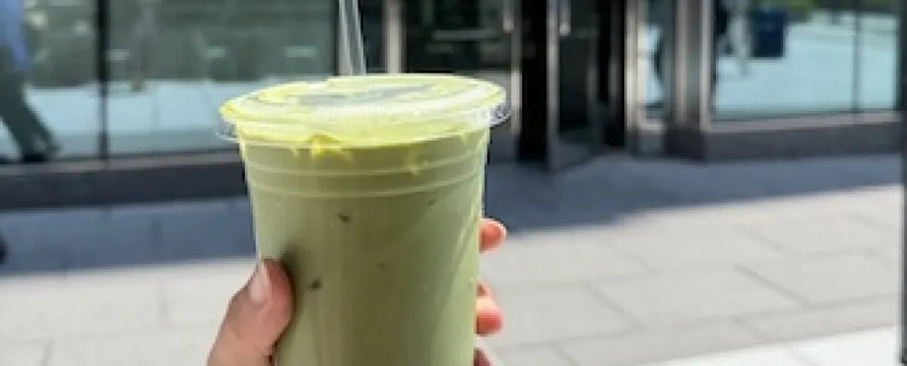 A hand holds up a to-go matcha