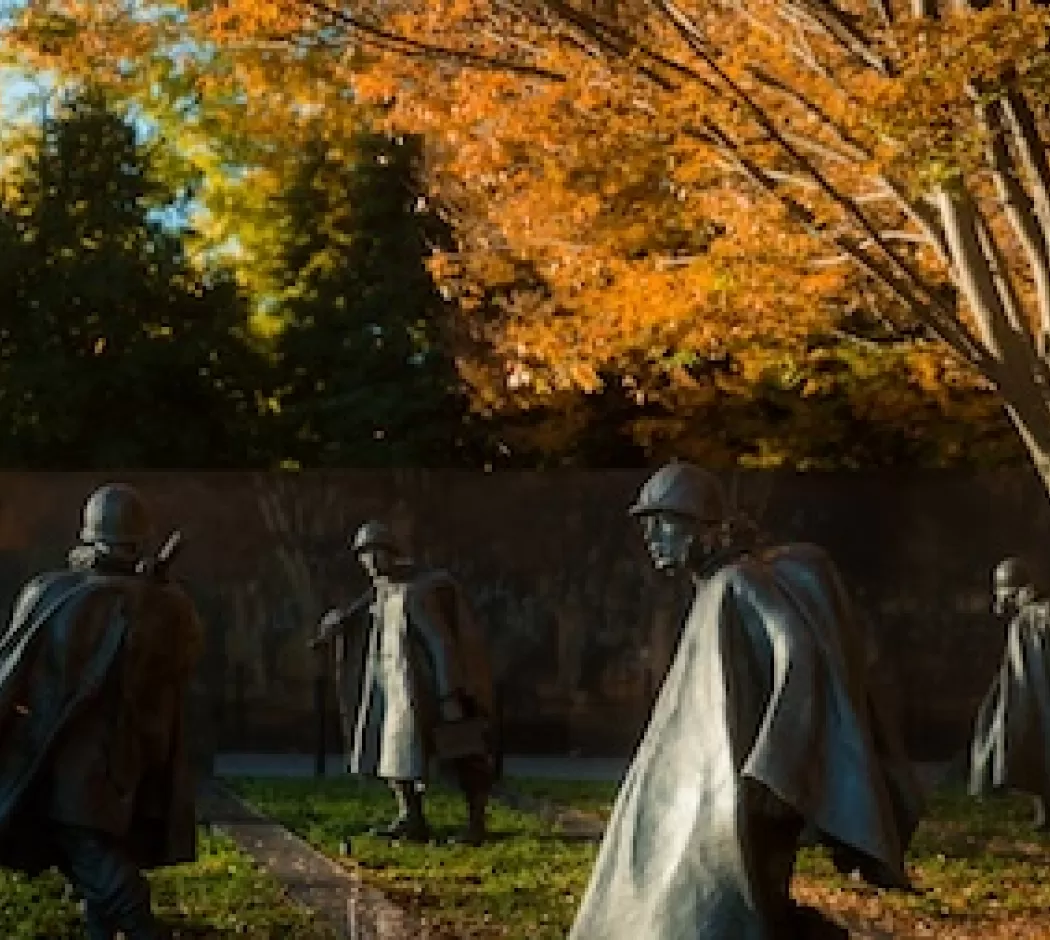 Several figures from the Korean War Veterans Memorial with autumn trees.