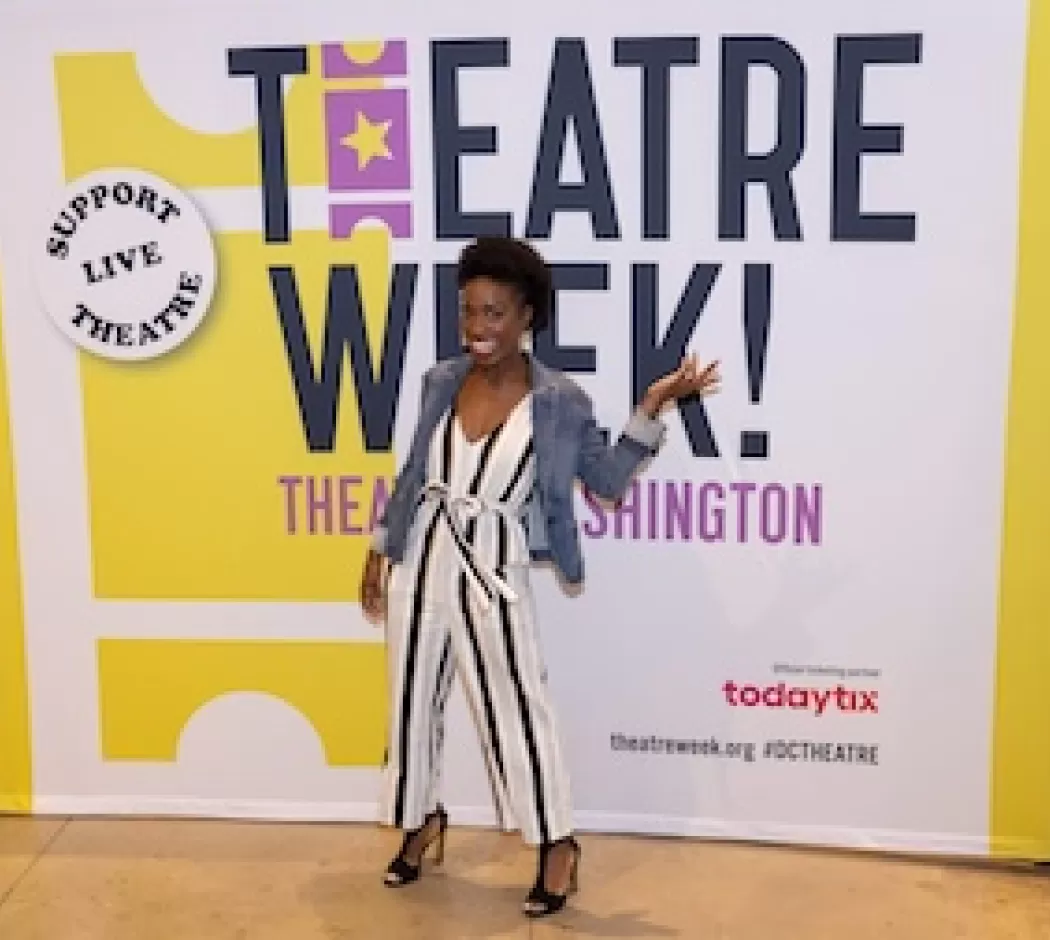 Woman posing in front of a Theatre Week banner.